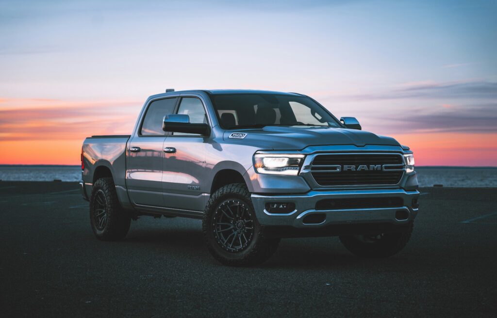 Silver pickup truck parked in front of the ocean at sunset