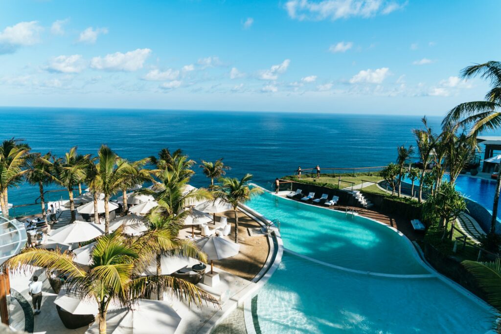 Upscale swimming pool with palm trees next to the ocean in Bali