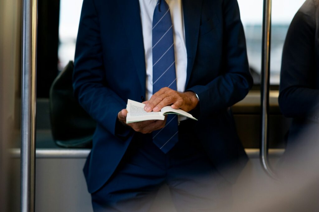 Businessman in blue suit holding a book on public transportation